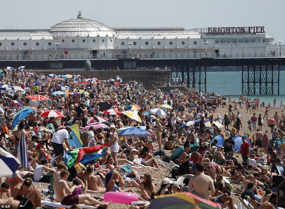 Beachgoers enjoy the sunshine and sea at a packed Brighton beach in East Sussex this afternoon