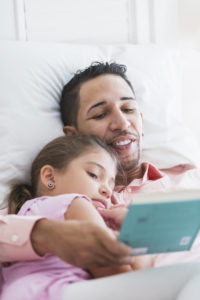 Father reading bedtime story to daughter