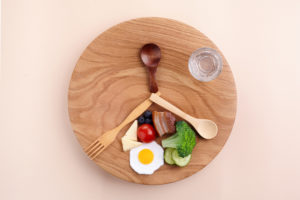 Intermittent fasting concept. Weight loss. Top view of plate with healthy foods and glass of water.
