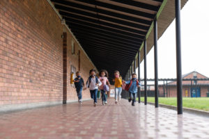 Group of children running at school wearing masks